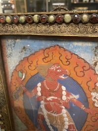 A Tibetan thangka in inlaid gilt brass frame, 19th C.